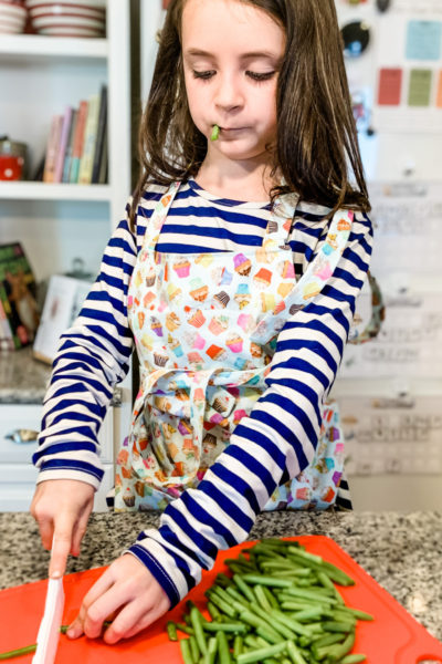 Five benefits of having kids help it the kitchen. From building vocabulary to enjoying fun new sensory experiences, cooking with little ones in the kitchen is so much fun! #cookingwithkids #kidscooking #bakingwithkids #kidsinthekitchen
